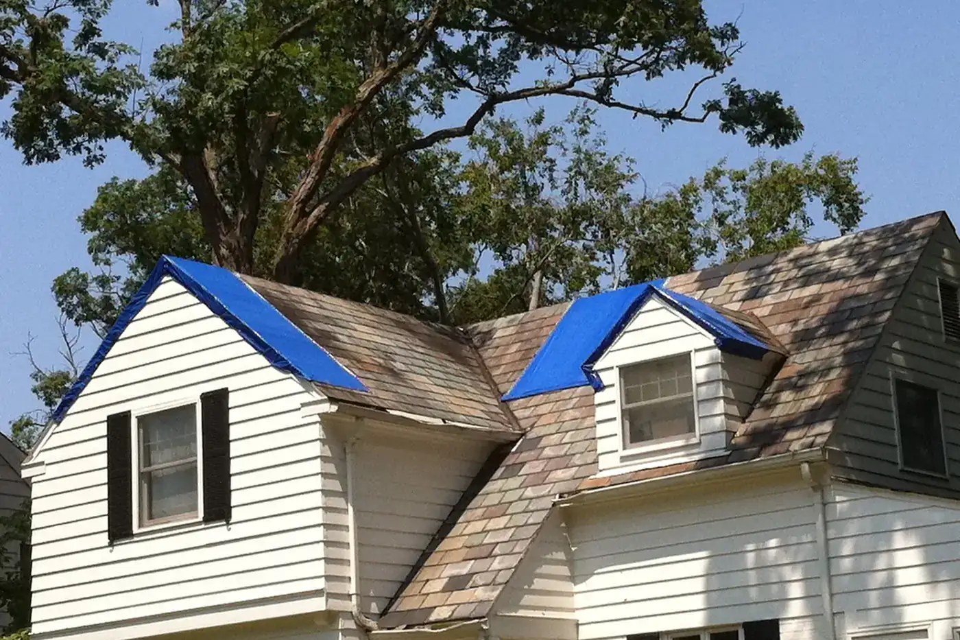 Blue tarps covering storm-damaged sections of a house roof after an August 2010 storm