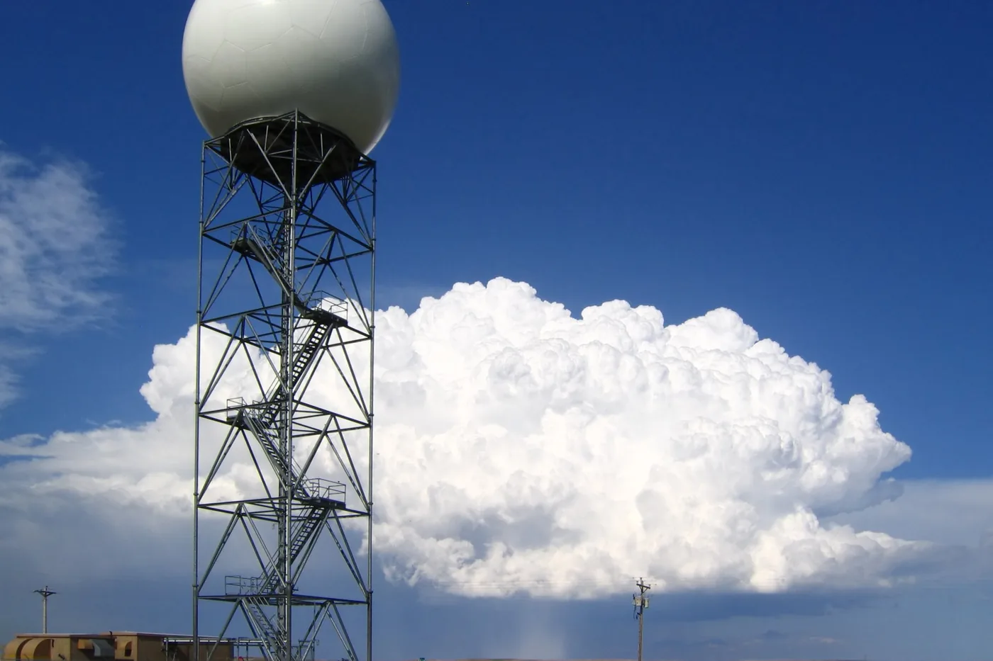 WSR-88D Doppler radar tower at New Underwood, South Dakota, with a distant thunderstorm dropping hail behind it