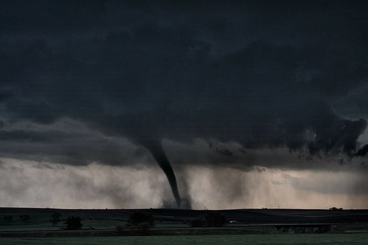 Tornado descending from a dark storm base over open country on the Great Plains