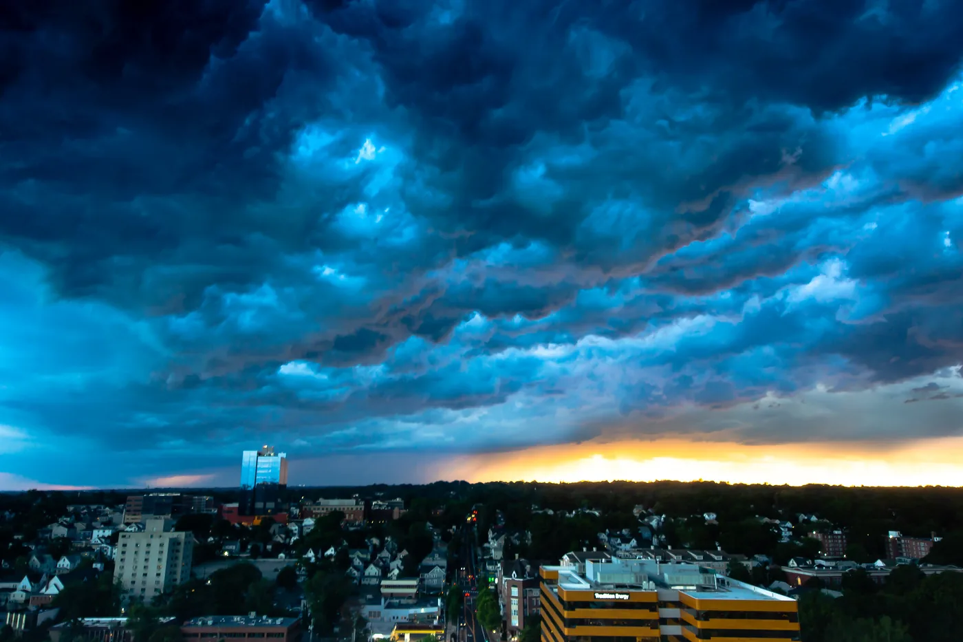 Roiling storm clouds over Stamford, Connecticut, with the evening light low on the horizon above the city's rooftops