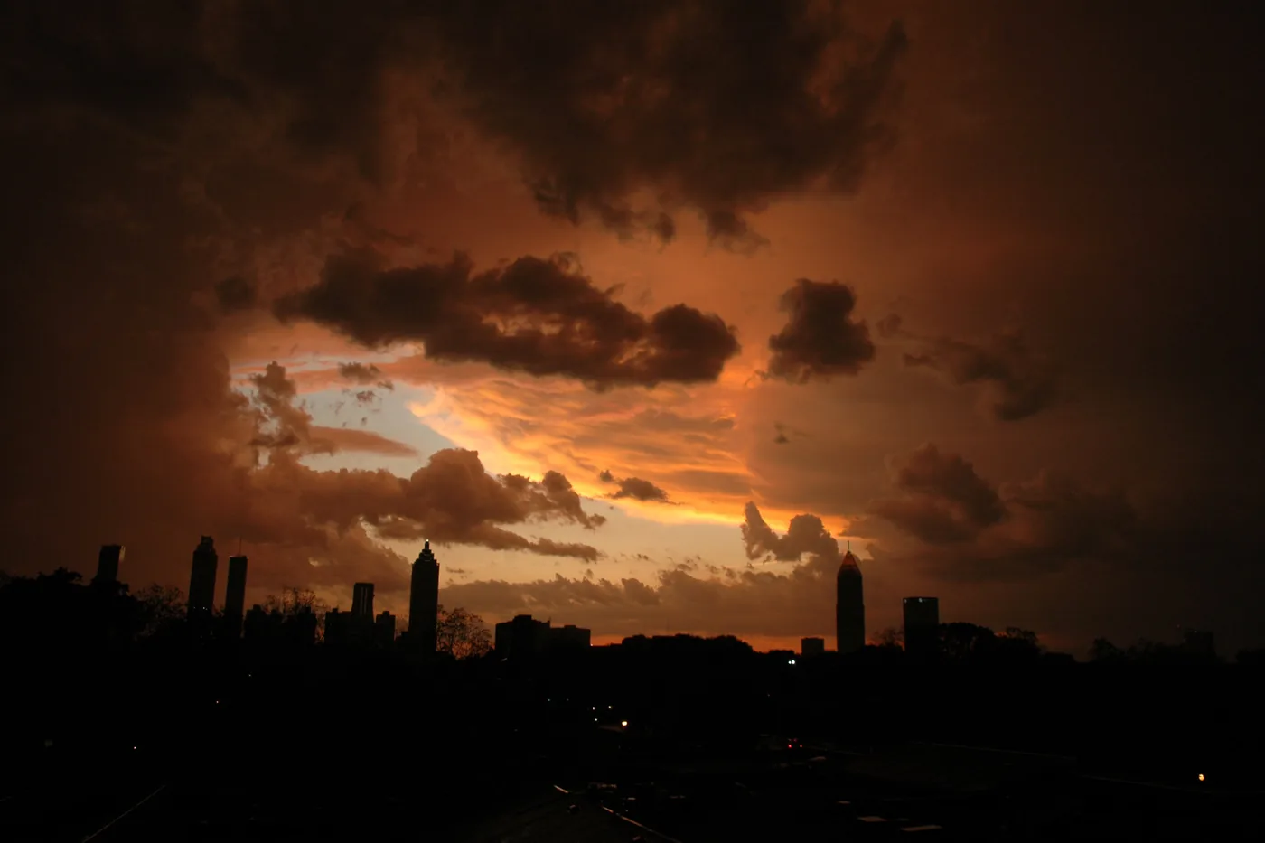 Atlanta skyline silhouetted against glowing clouds during a massive thunderstorm, seen from an apartment balcony
