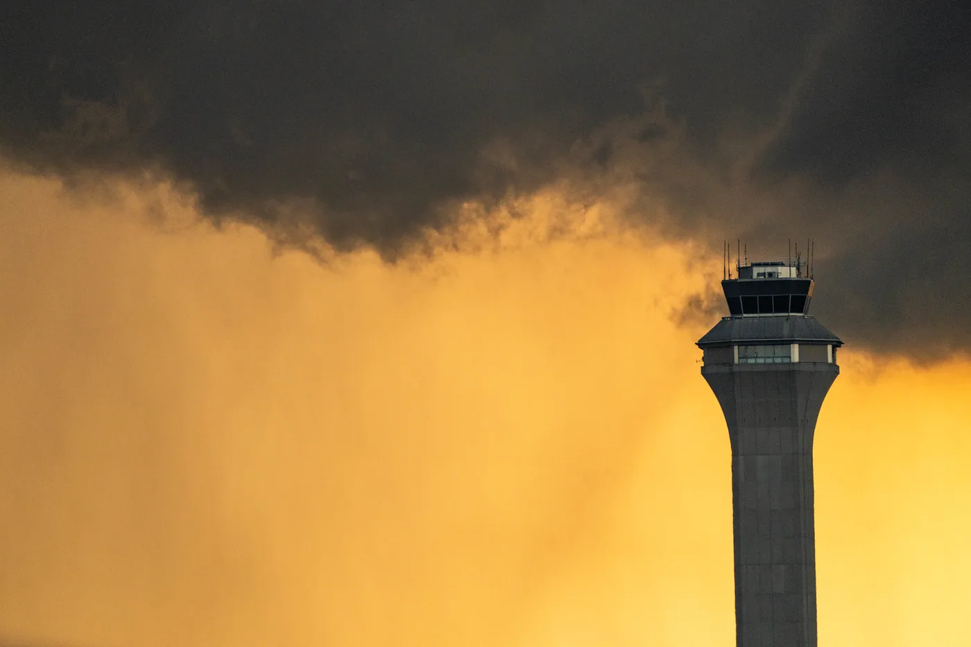 Rain storm darkening the sky behind the control tower at Newark airport at sunset