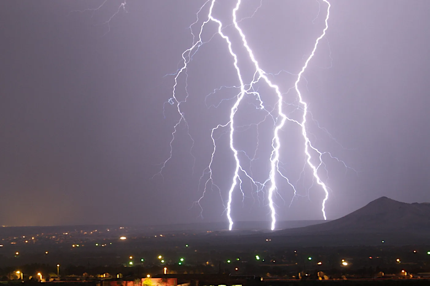 Multiple lightning bolts striking beyond the lights of Las Cruces, New Mexico, at night