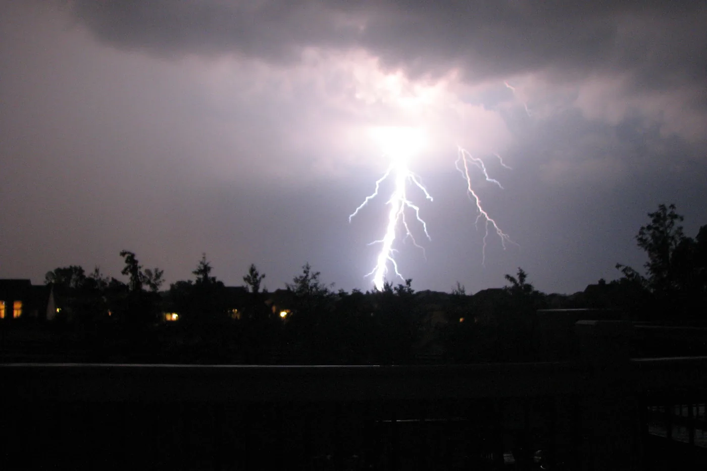 Lightning bolt striking behind treetops at night in Powell, a suburb of Columbus, Ohio