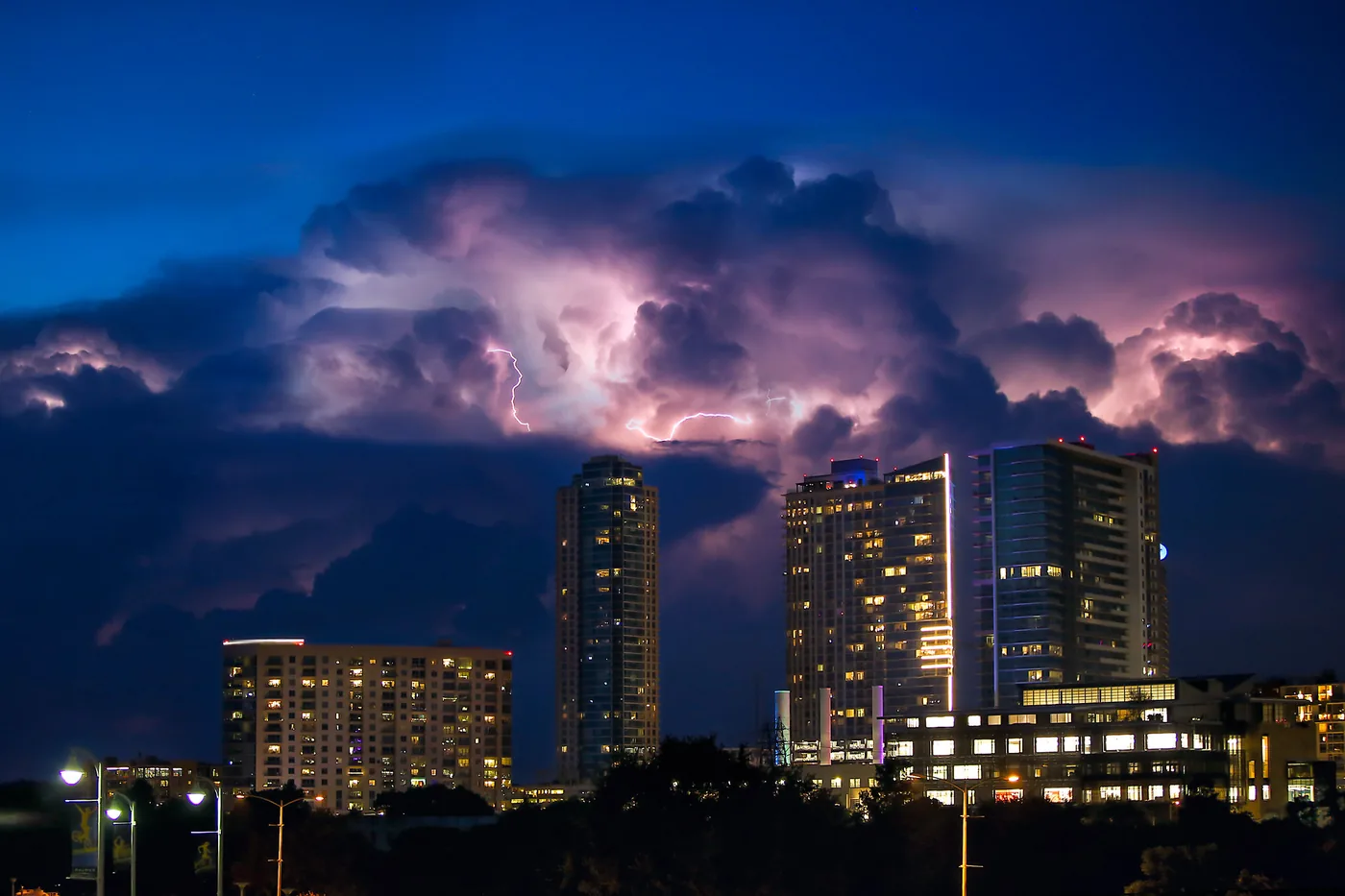 Lightning lighting up storm clouds behind high-rise towers in Austin, Texas