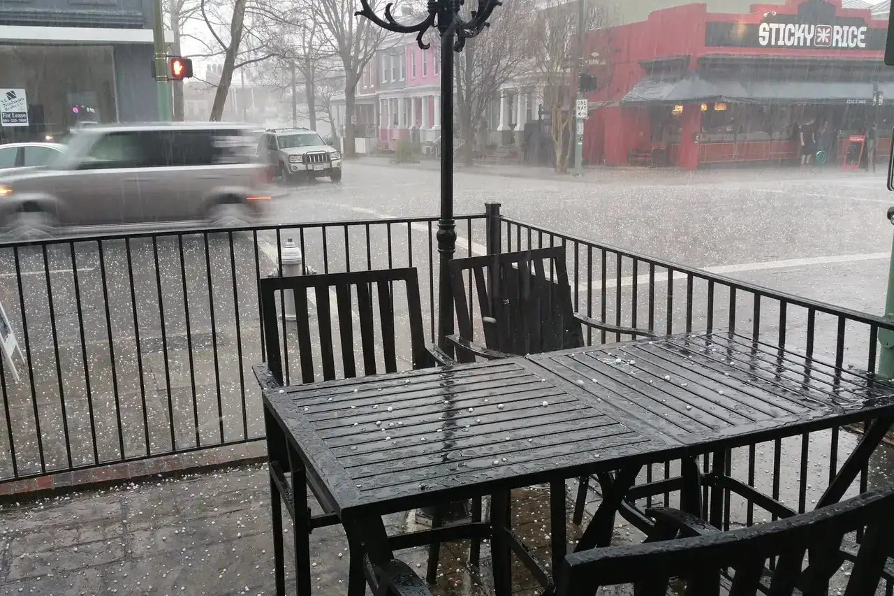 Hail and heavy rain pelting a street-side café patio during a hailstorm in Richmond, Virginia