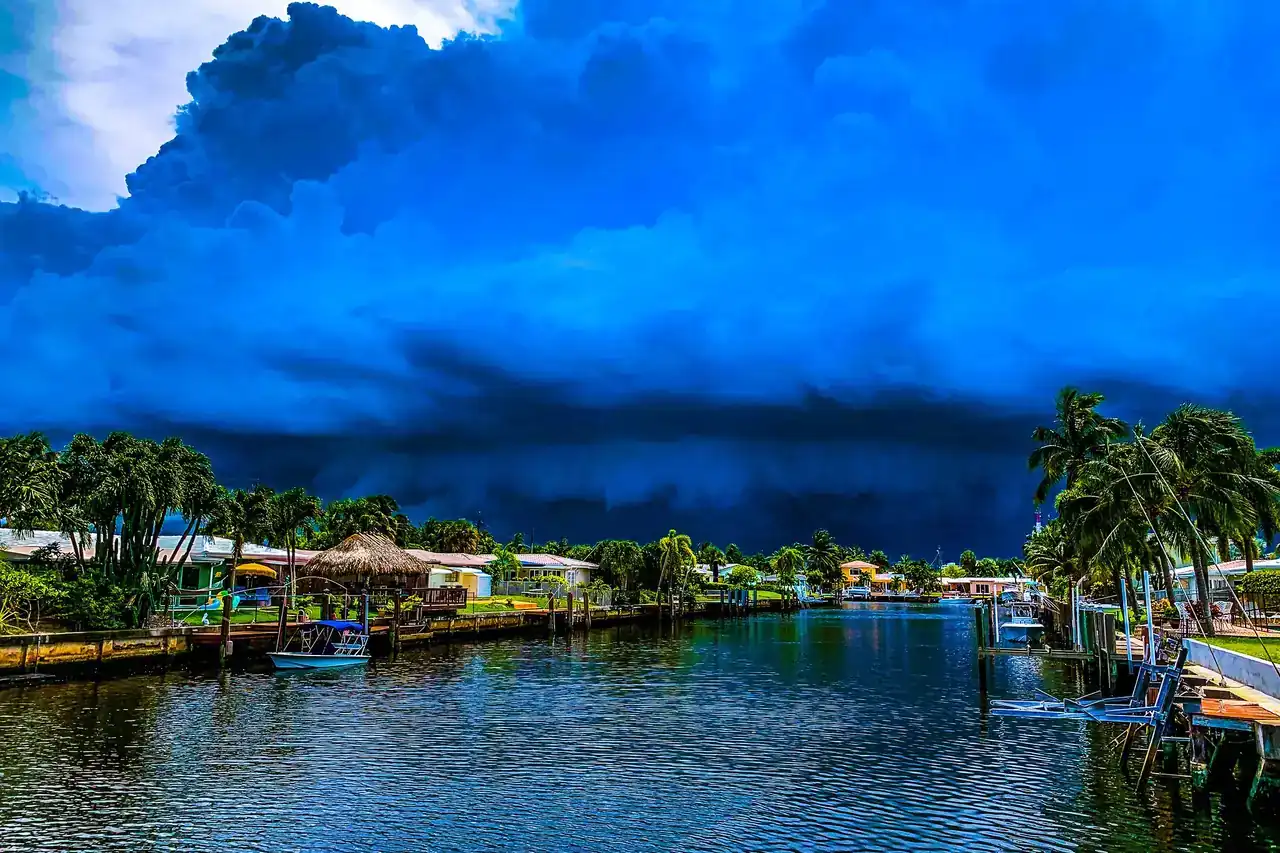 Dark thunderstorm clouds over a palm-lined residential canal in Florida