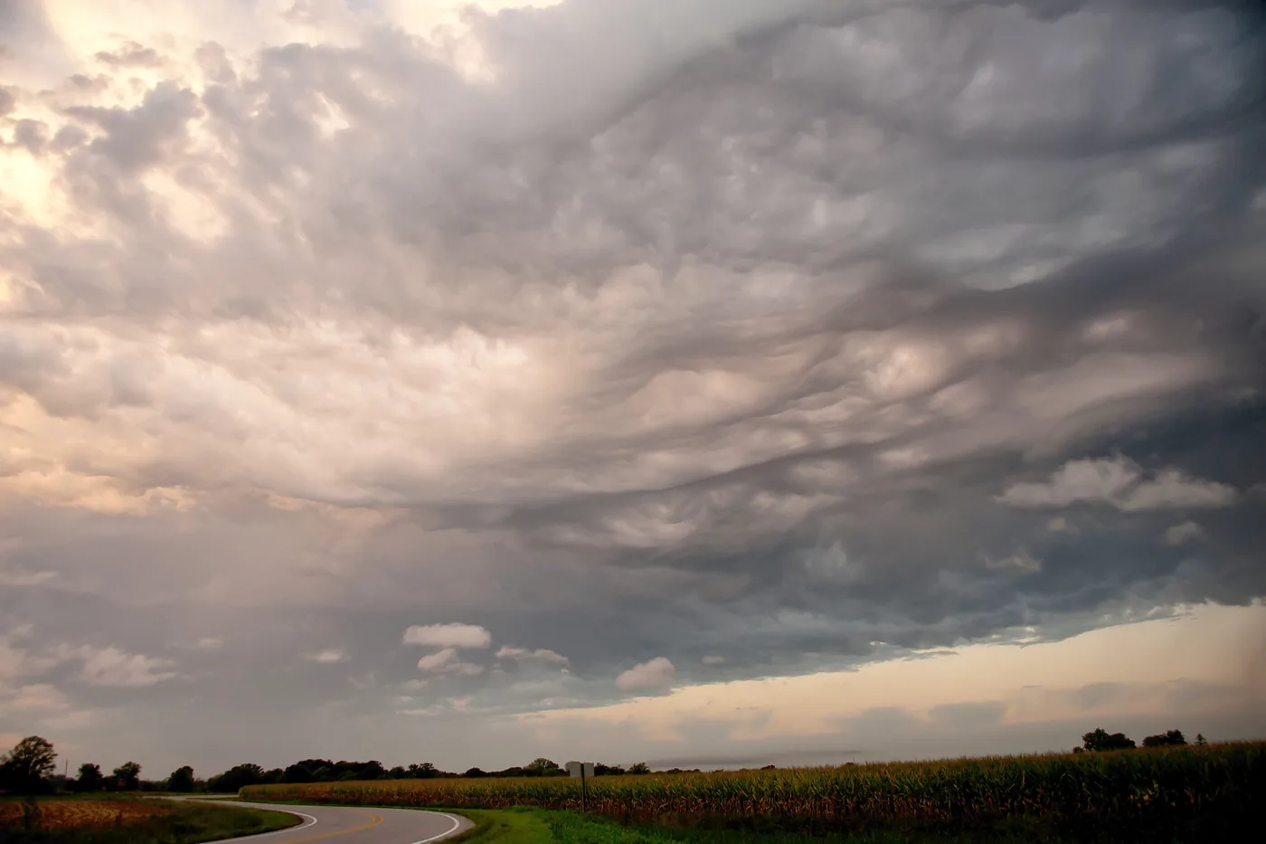 Rough, sagging storm clouds over a country road and farmland in central Iowa