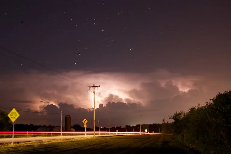 Lightning from an approaching night storm lighting up power lines and a rural road in upstate New York