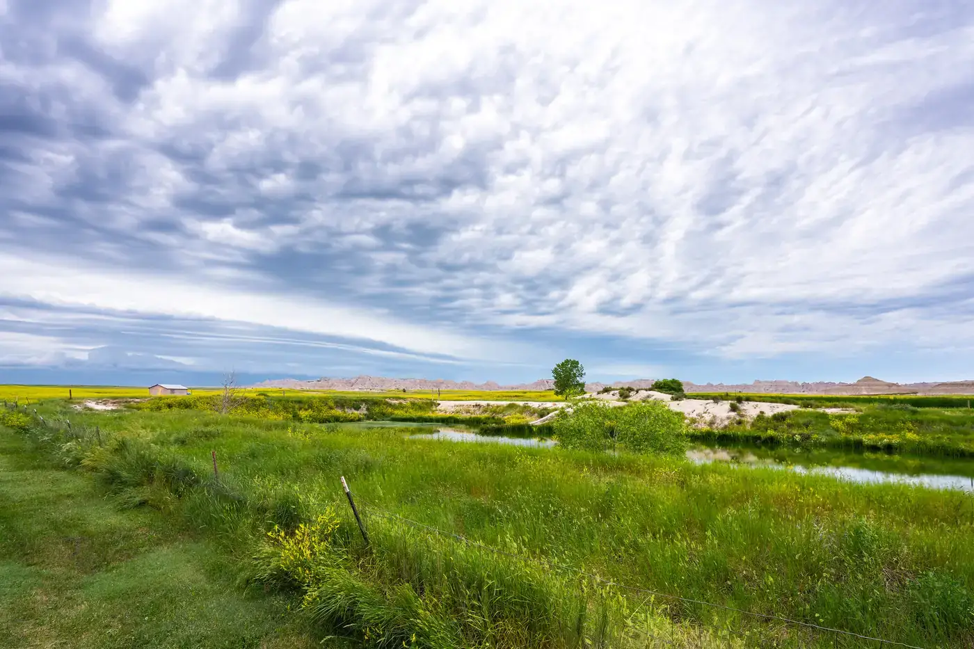 Clouds gathering over grassland and distant eroded buttes at Badlands National Park near Interior, South Dakota