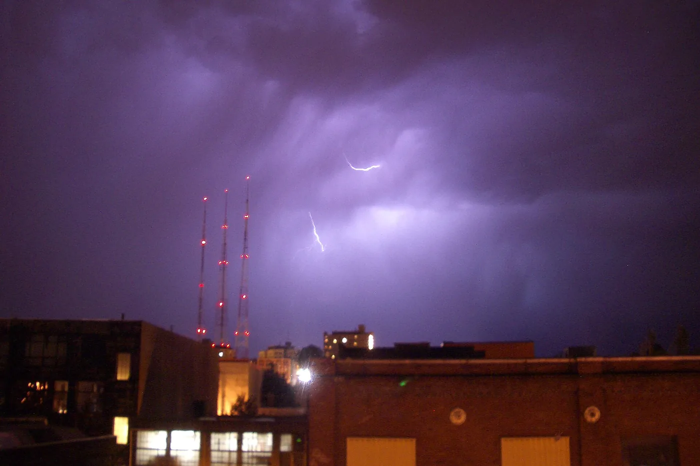 Lightning inside a thunderhead east of Seattle, behind radio towers and rooftops at night