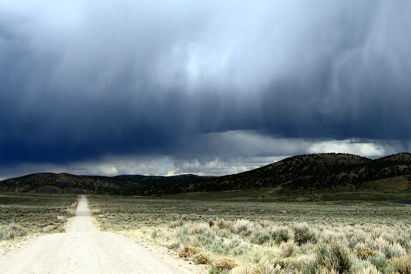 Dark storm with falling rain over sagebrush hills along a dirt back road in Wyoming