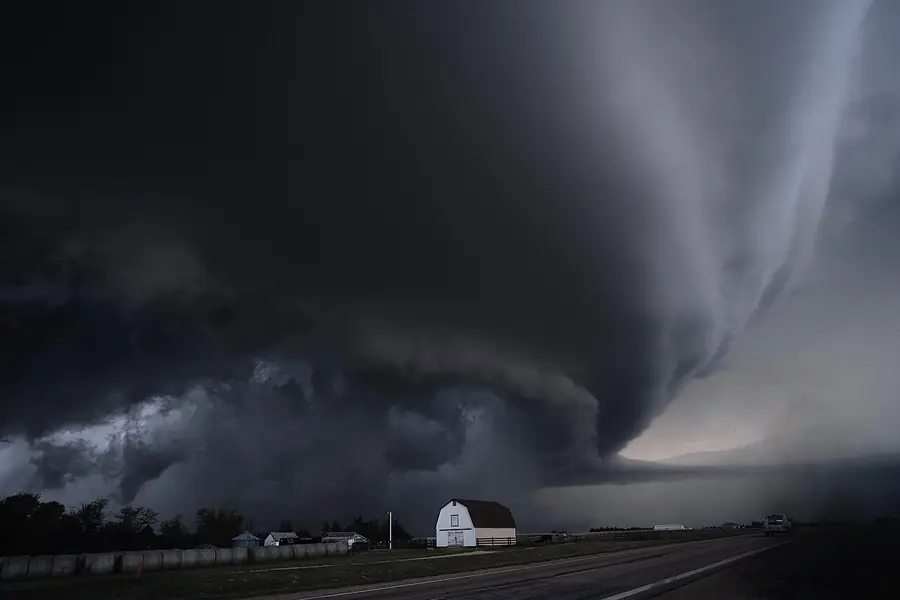 Supercell thunderstorm darkening the sky over a rural property on the Plains